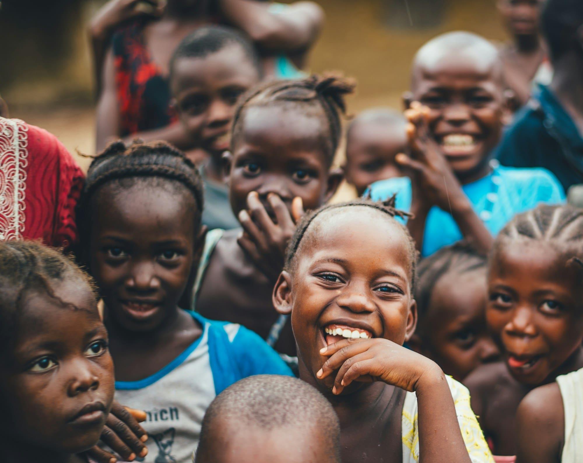 A group of smiling children crowded together, looking towards the camera