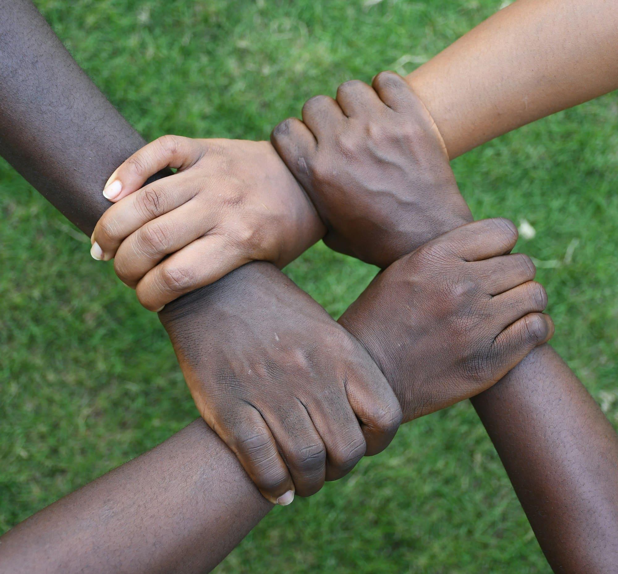 Four hands clasp each other's wrists in a circle of support