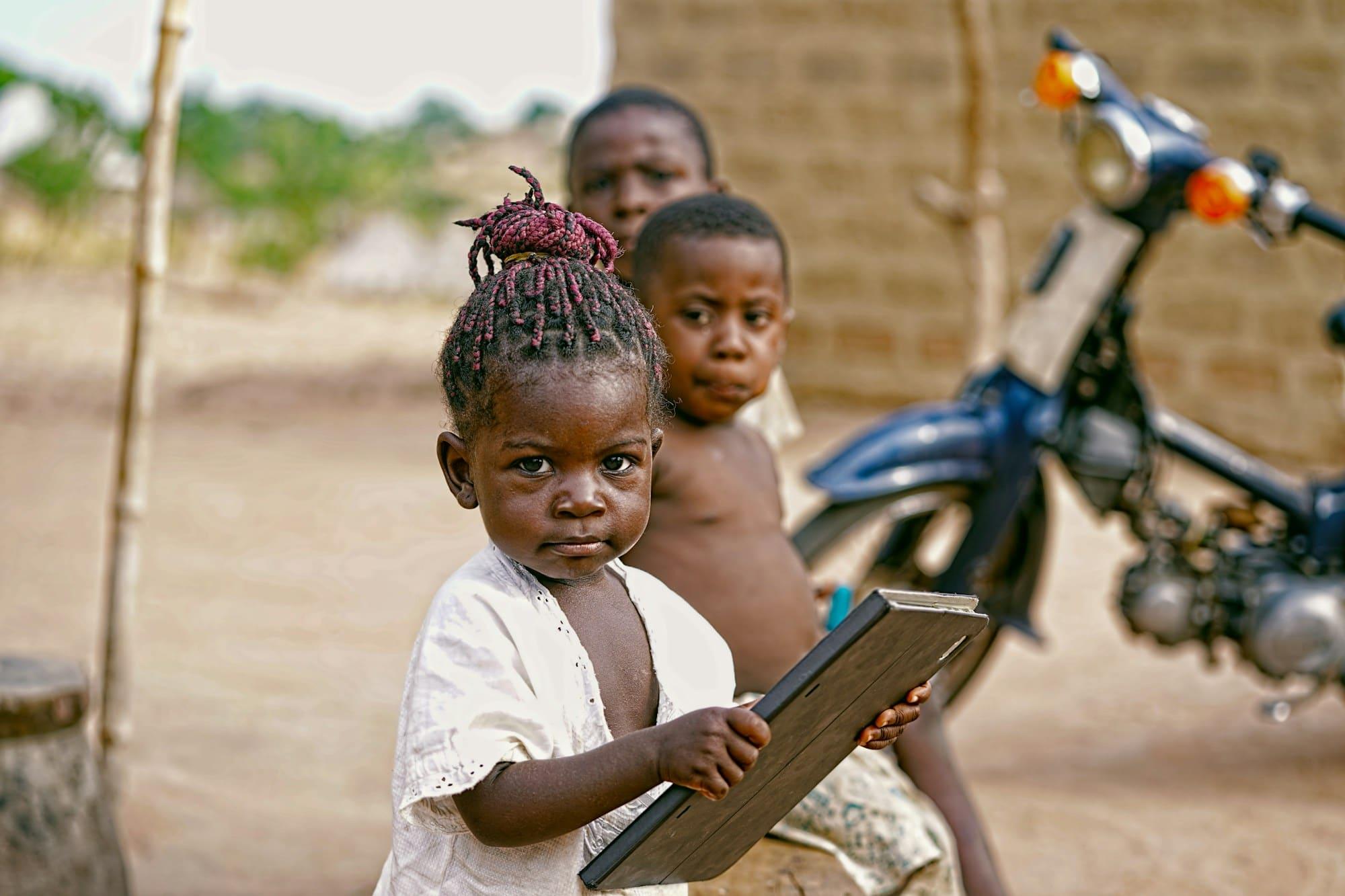 A little girl holds a writing slate as an older boy looks on